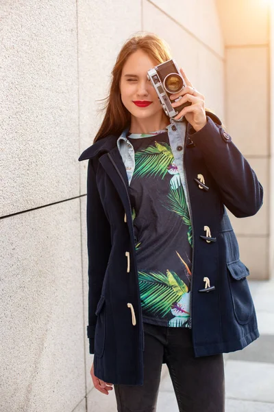 Glücklich Hipster-Mädchen macht Foto mit Retro-Kamera auf der Straße der Stadt. Sonneneruption — Stockfoto