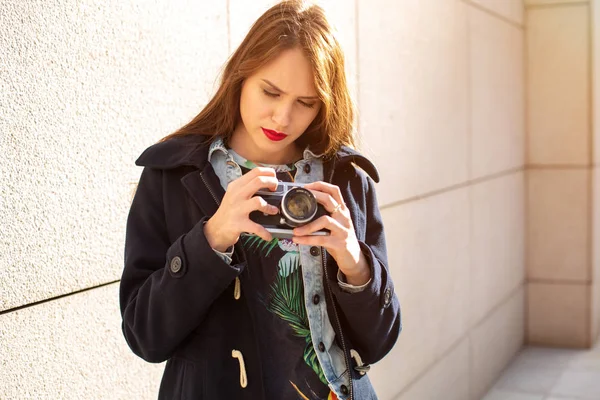 Glücklich Hipster-Mädchen macht Foto mit Retro-Kamera auf der Straße der Stadt. Sonneneruption — Stockfoto