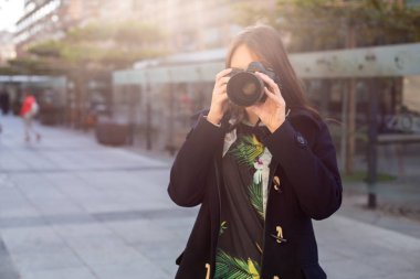 Çekici turist kadın fotoğrafçı ile fotoğraf makinesi, şehirde sokak açık. Güneş parlaması