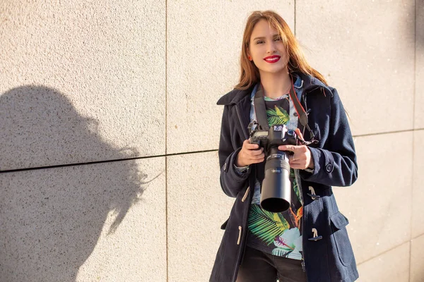 Счастливая женщина в отпуске фотографирует с камерой на городской улице. Солнечная вспышка — стоковое фото