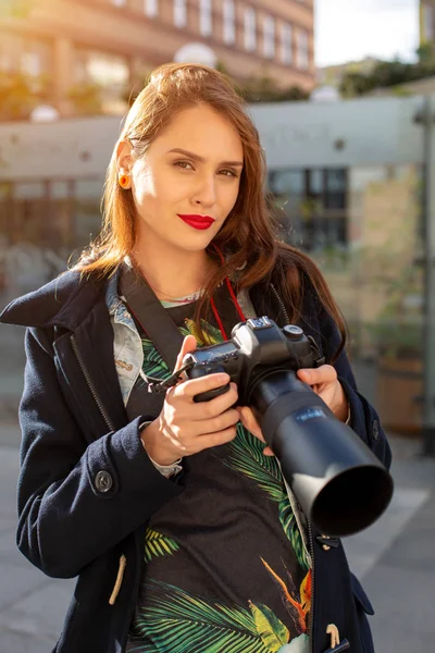 Ελκυστική τουριστική γυναίκα φωτογράφος με φωτογραφική μηχανή, εξωτερική σε δρόμο της πόλης. Ήλιος φωτοβολίδα — Φωτογραφία Αρχείου