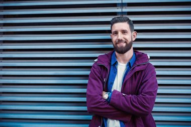 Yakışıklı genç moda giysiler içinde saç modeli ile demir duvar ve kameraya bakarak yakın duruyor