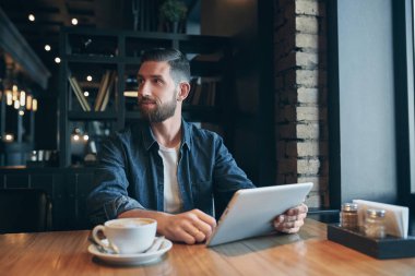 kafede kahve içme ve tablet bilgisayarı kullanan genç adam