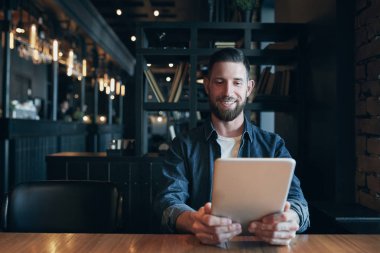 Öğle yemeği zamanı sırasında şehir kafede kahve içme ve tablet üzerinde çalışan Modern hipster işadamı
