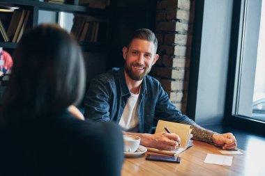 Adam el ahşap bir masa üstünde defter üzerinde yazılı kalem ile.