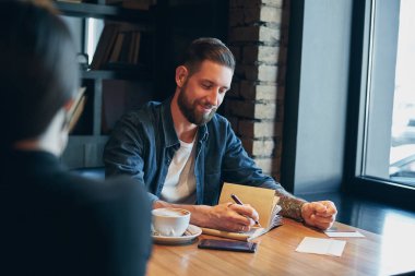 Adam el ahşap bir masa üstünde defter üzerinde yazılı kalem ile.