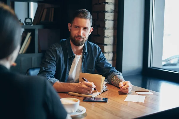 Mano de hombre con la escritura de la pluma en el cuaderno en una mesa de madera . — Foto de Stock