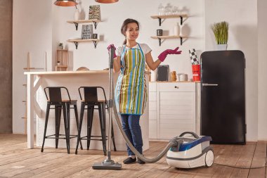 Genç kadının ev mutfak katında elektrikli süpürge kullanarak yapması temizlik görevleri ve ev işleri, titiz iç.