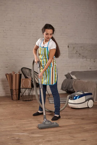 Mujer joven que usa aspiradora en el piso de la sala de estar en casa, haciendo tareas de limpieza y tareas, interior meticuloso . — Foto de Stock
