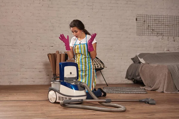 Mujer joven abriendo aspiradora, posible fracaso. Trabajo doméstico en casa . — Foto de Stock