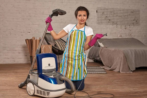 Mujer joven abriendo aspiradora, posible fracaso. Trabajo doméstico en casa . — Foto de Stock