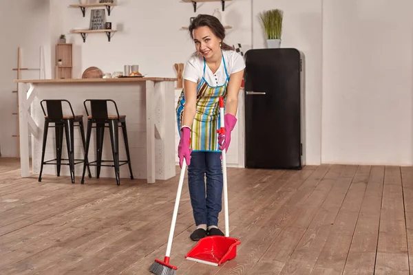 Mujer joven barriendo piso en la cocina — Foto de Stock