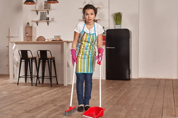 Mujer joven barriendo piso en la cocina — Foto de Stock