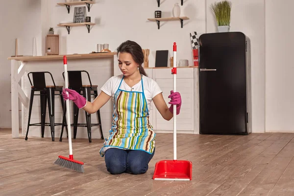 Mujer joven barriendo piso en la cocina — Foto de Stock