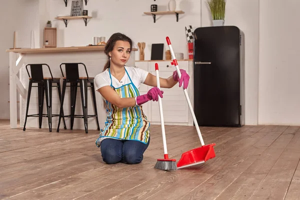 Young woman sweeping floor on the kitchen — Stock Photo, Image