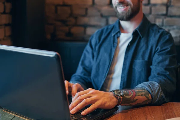 A fiatalember kávét iszik city café, ebédre idő alatt, és dolgozik a laptop. Közelről — Stock Fotó