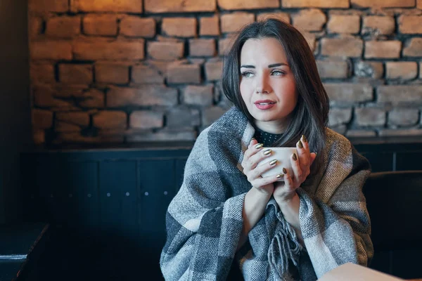 Retrato de jovem senhora com cabelo encaracolado escuro sonhadamente fechando os olhos com copo nas mãos. Menina agradável sentado no café com xícara de café — Fotografia de Stock