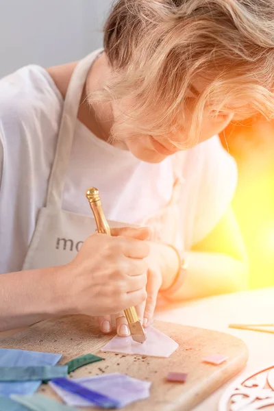 Kunstenaar snijden vellen gekleurd glas in kleine mozaïek vierkanten. Close-up — Stockfoto