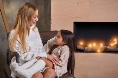 Güzel anne kadın beyaz kazaklı küçük kızı sarılmak. Neşeli oynak ruh ve aile içinde sevgi.