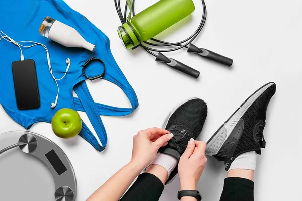 Bovenaanzicht van vrouw handen koppelverkoop schoenen met sport apparatuur op witte achtergrond — Stockfoto
