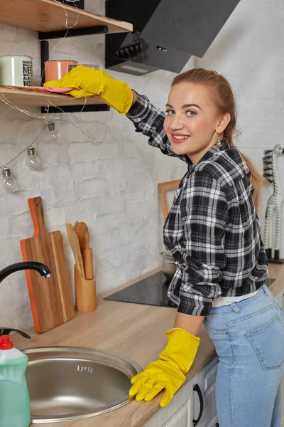 Woman in gloves cleaning furniture with rag at home kitchen. Concept of housework.