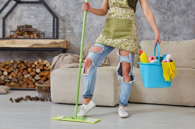 Temizlik hizmeti. Kova Süngerler, kimyasallar şişeleri ve paspas sopa ile. Oturma odası, bir paspas ile bir kadının Resim kırpılmış