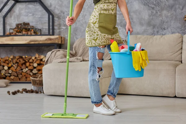 Servicio de limpieza. Cubo con esponjas, botellas de productos químicos y bastón de fregar. Imagen recortada de una mujer con una fregona en el salón — Foto de Stock