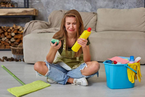 Γυναίκα νοικοκυρά αισθάνονται κουρασμένοι να κάθονται στο πάτωμα στο σαλόνι μετά τον καθαρισμό στο σπίτι. — Φωτογραφία Αρχείου