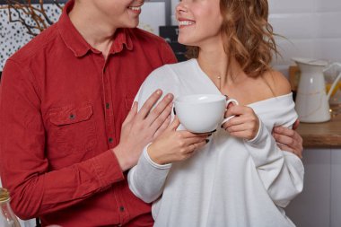 Mutlu genç güzel çift mutfak birbirlerine sarılma. Onlar kahve içme keyfini çıkarın