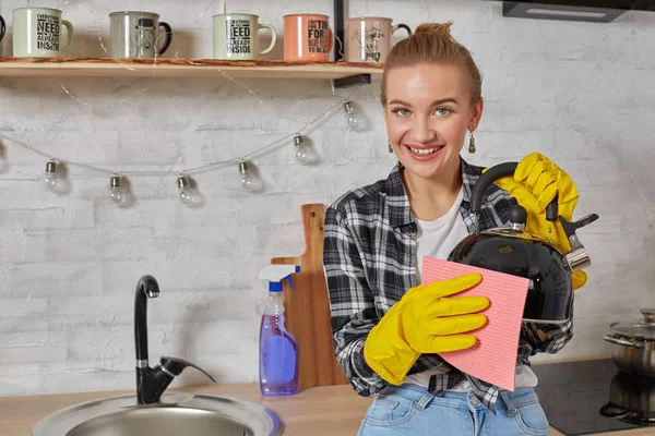 Domestic service and housekeeping concept, happy blonde lady cleaning kitchen kettle.