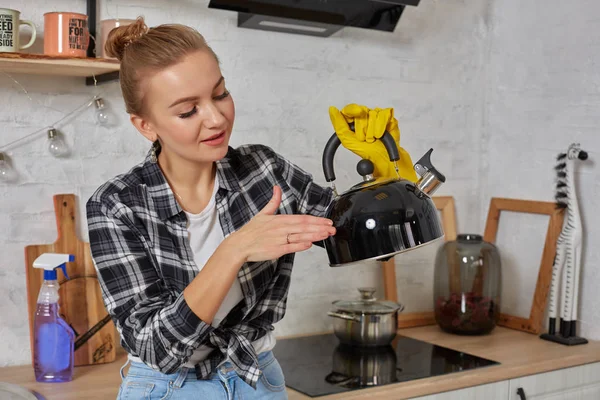 Domestic service and housekeeping concept, happy blonde lady cleaning kitchen kettle, close-up of hands in rubber gloves holding spray