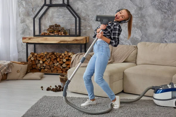 Joven alegre disfrutando cantando en solitario con aspiradora mientras limpia la casa — Foto de Stock