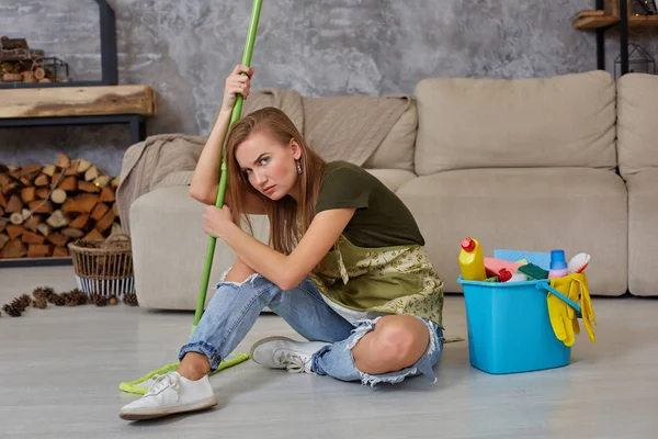 Mulher dona de casa se sentir cansado sentado no chão na sala de estar após a limpeza em casa . — Fotografia de Stock