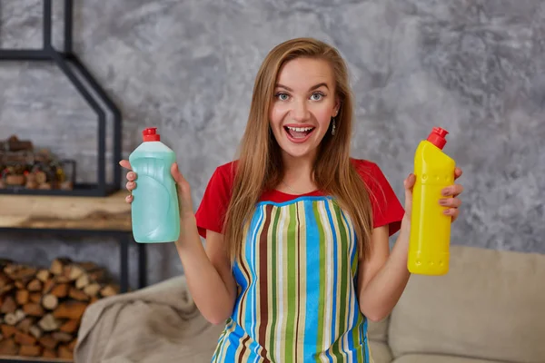 Γυναίκα συγκρίνει δύο μπουκάλι απορρυπαντικού στο σπίτι καθαρισμού στο σαλόνι. Εργασία στο σπίτι. — Φωτογραφία Αρχείου