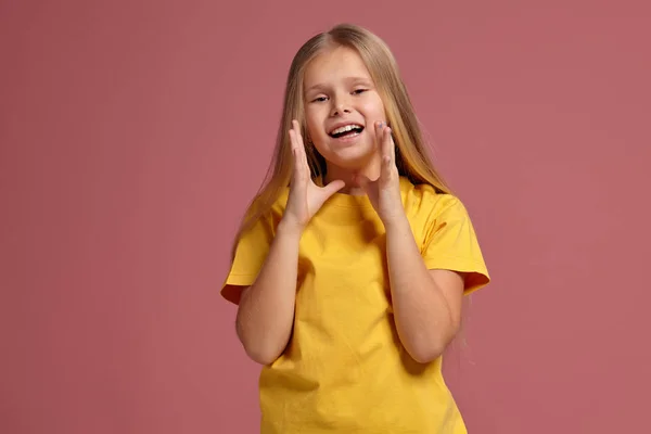 Μικρό κορίτσι σε ένα κίτρινο μπλουζάκι. Κοιτάζοντας δειλά — Φωτογραφία Αρχείου