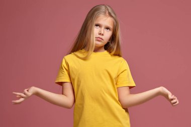 mercan bir arka plan üzerinde sarı bir tişört, küçük kız. cevabı bilmiyor