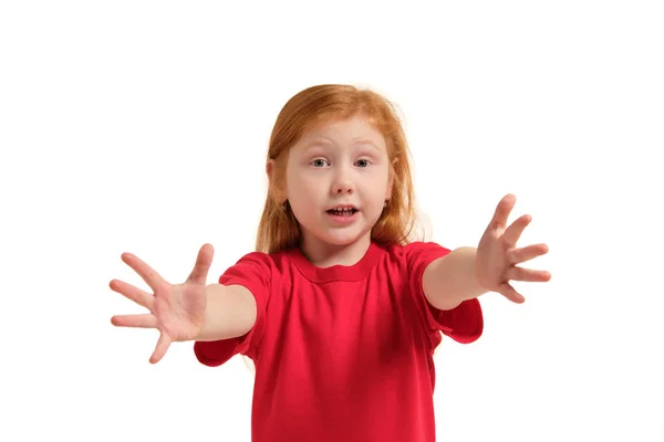 Портрет милой рыжеволосой эмоциональной маленькой девочки, изолированной на белом, пытающейся дотянуться вперед — стоковое фото