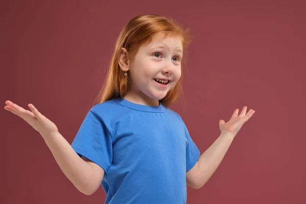 Портрет милой рыжеволосой эмоциональной маленькой девочки на красном фоне — стоковое фото