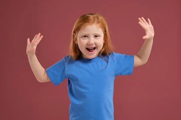 Портрет милой рыжеволосой эмоциональной маленькой девочки на красном фоне — стоковое фото