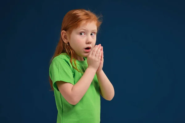 Cerca de la foto de la niña pelirroja emocional posando ante la cámara en el fondo azul —  Fotos de Stock