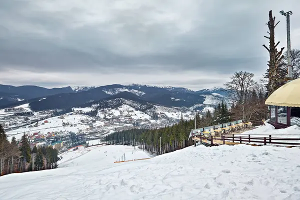 Panorama von Skigebiet, Piste, Menschen am Skilift, Skifahrer auf der Piste zwischen grünen Kiefern und Schneelanzen. — Stockfoto