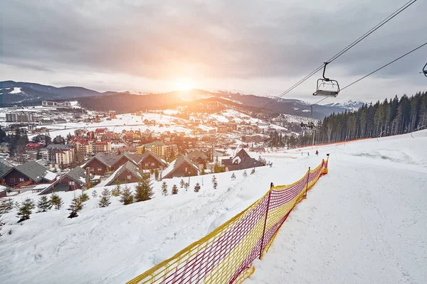 Panorama von Skigebiet, Piste, Menschen am Skilift, Skifahrer auf der Piste zwischen grünen Kiefern und Schneelanzen. — Stockfoto