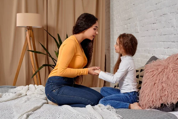 Liebe zu junger Mutter und Tochter. Sie sitzen zu Hause auf dem Bett und haben Spaß — Stockfoto