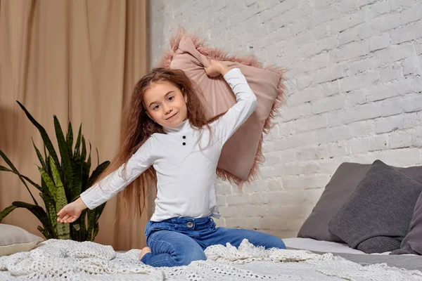 Портрет чарівної емоційної дівчинки на ліжку, з подушкою — стокове фото