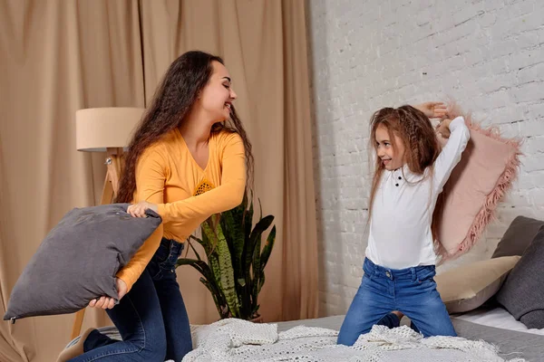 Mom and daughter fooling around with pillow fights