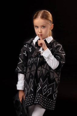 Karanlık bir panço, siyah çizmeler ve onun elinde bir debriyaj küçük kız