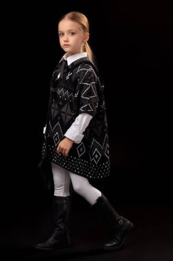 Karanlık bir panço, siyah çizmeler ve onun elinde bir debriyaj küçük kız