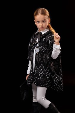 Karanlık bir panço, siyah çizmeler ve onun elinde bir debriyaj küçük kız