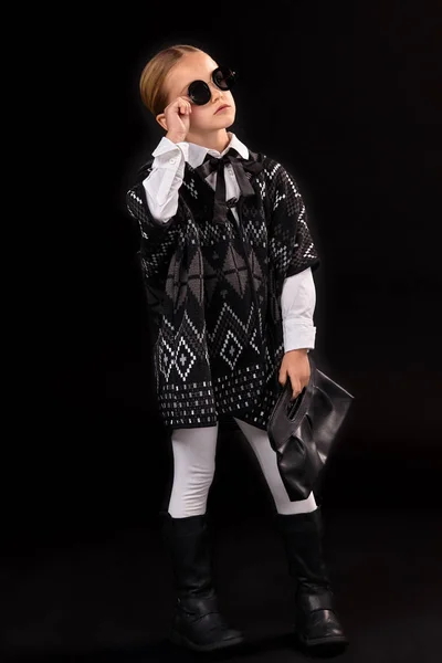 Malá holčička v černé brýle, tmavé pončo, černé boty a spojky v ruce — Stock fotografie