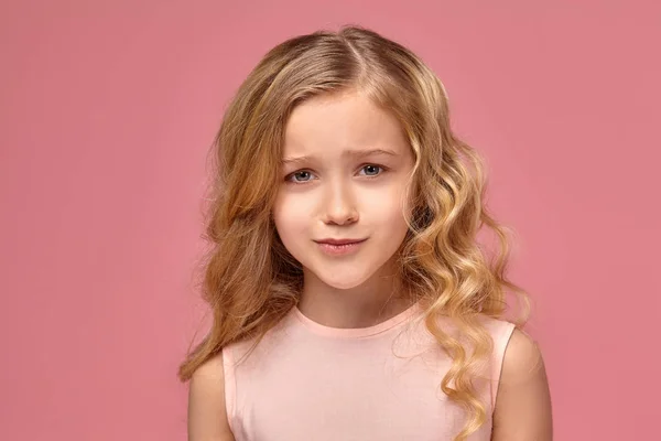 Niña con el pelo rubio rizado, en un vestido rosa está posando para la cámara —  Fotos de Stock